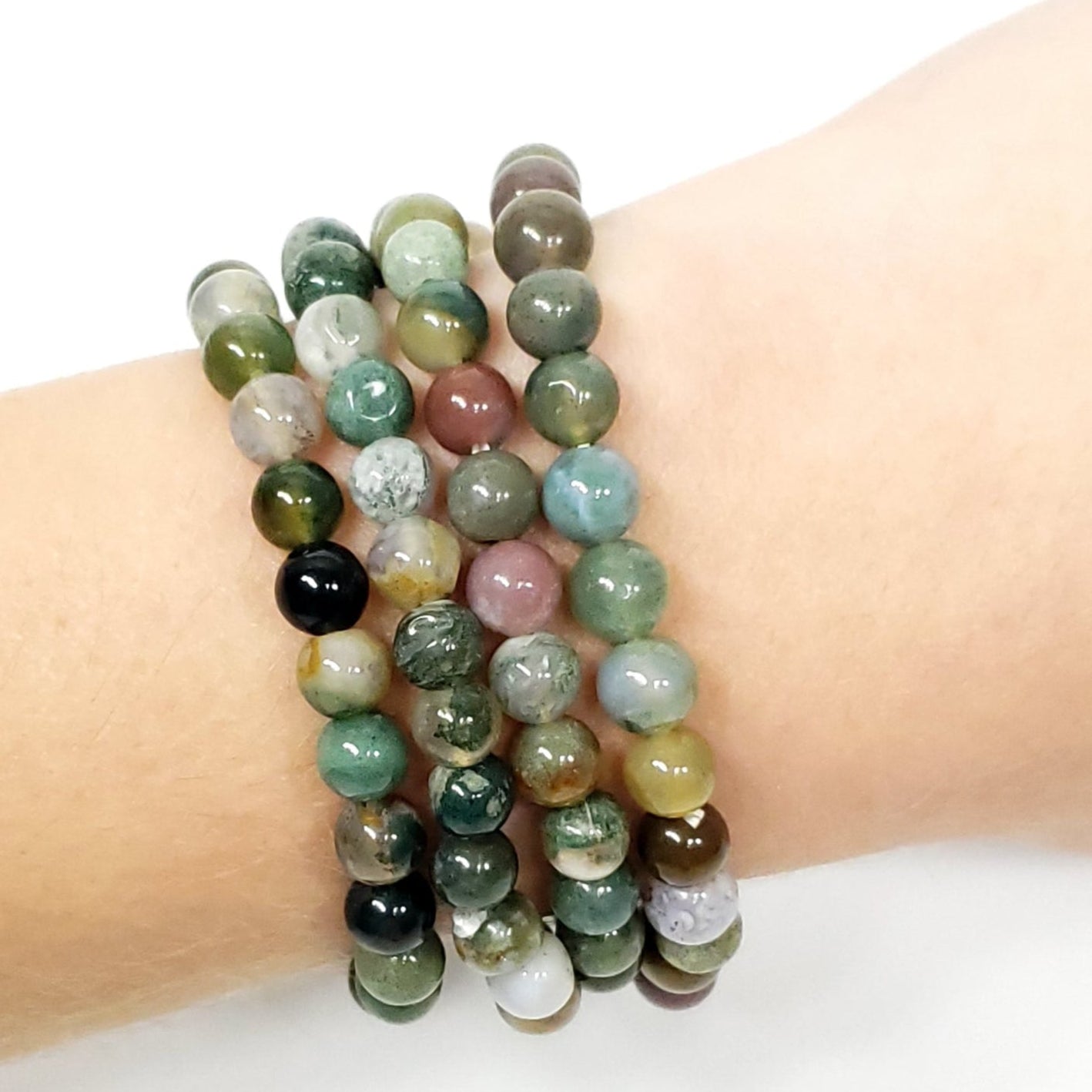 Multicolored beaded bracelets on a wrist against a white background