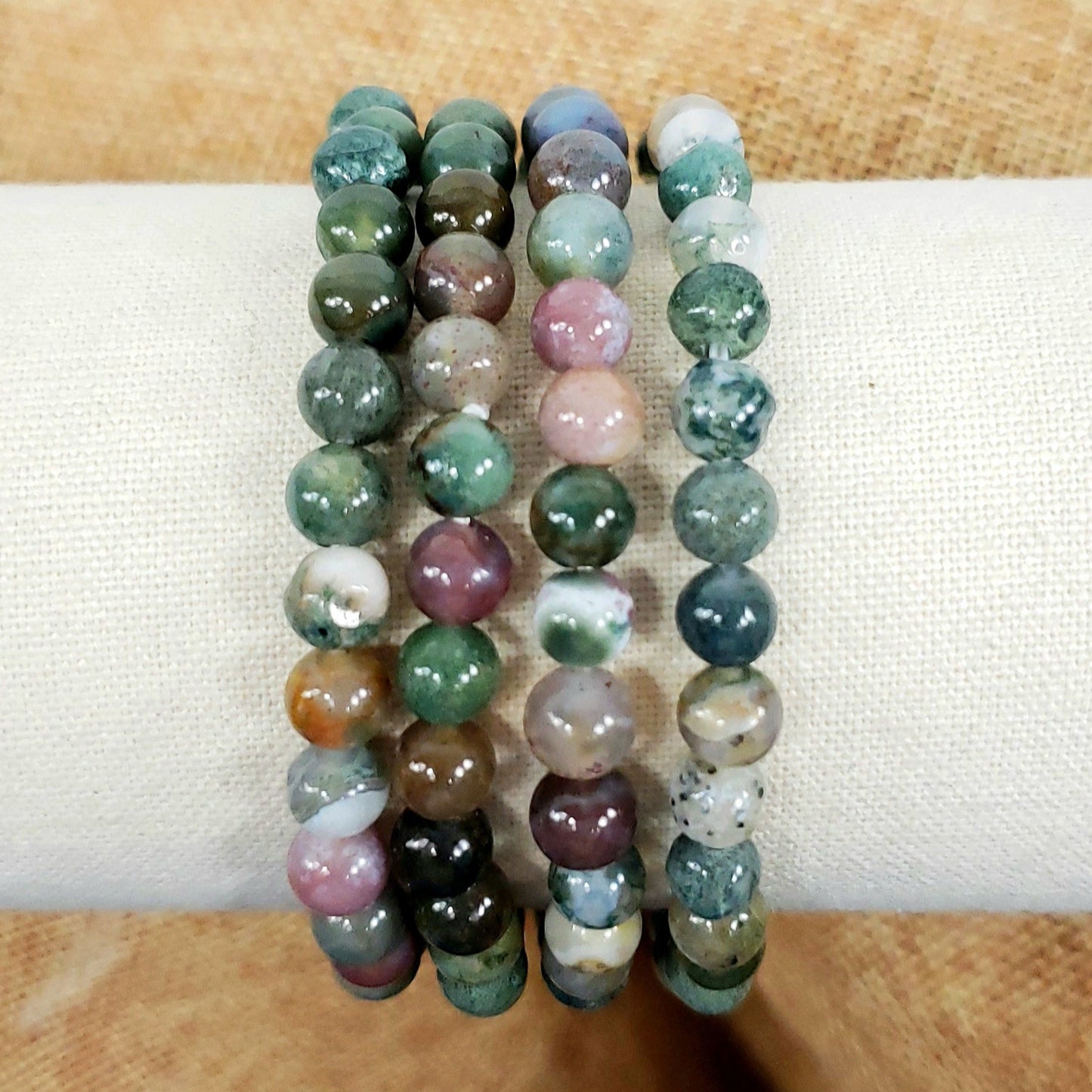 Set of three beaded bracelets with multicolor stones on a white surface.