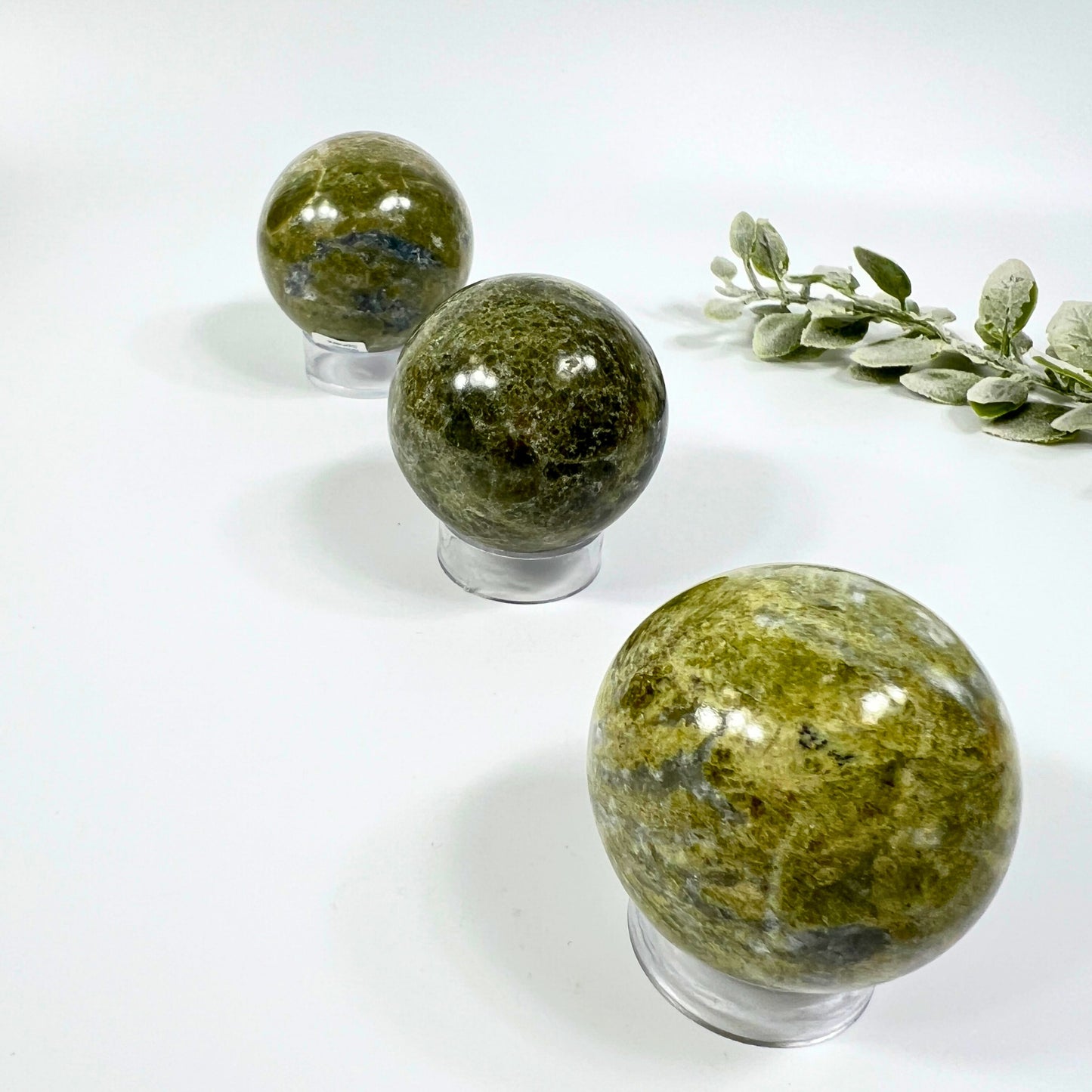 Three green stone spheres on stands with a white background