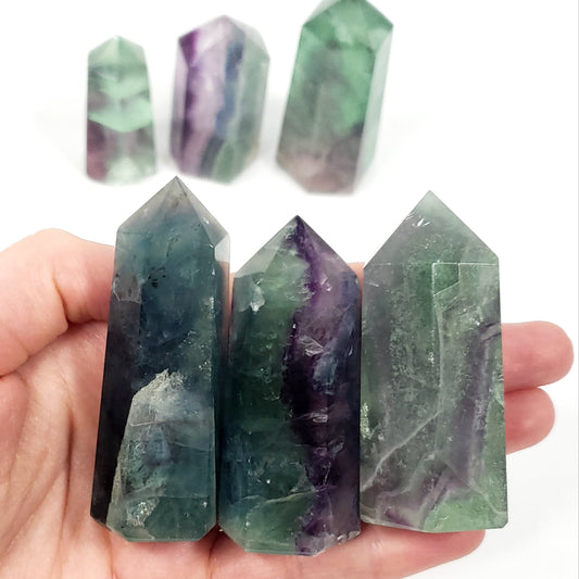 Hand holding a stack of green and purple crystal points on a white background