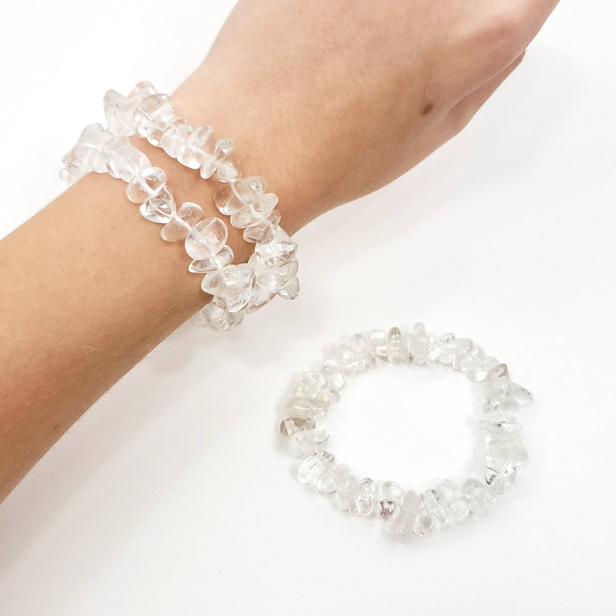A set of clear crystal tumbled stone bracelets, shown on a person's wrist and laid flat on a white surface.