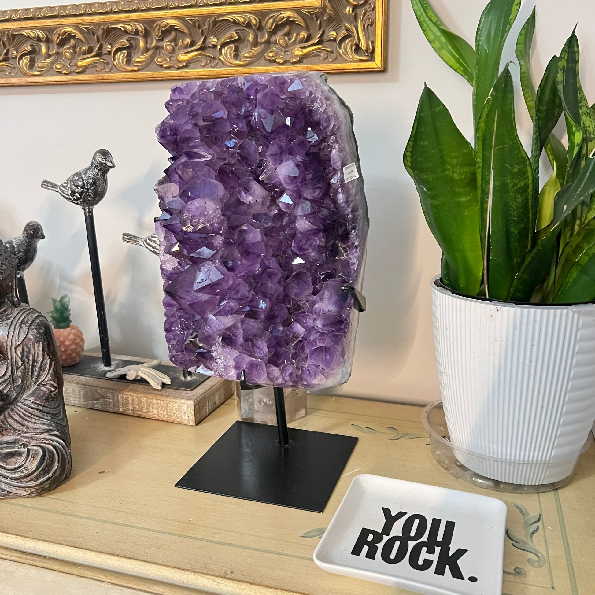 Amethyst crystal on a stand with decorative items on a table