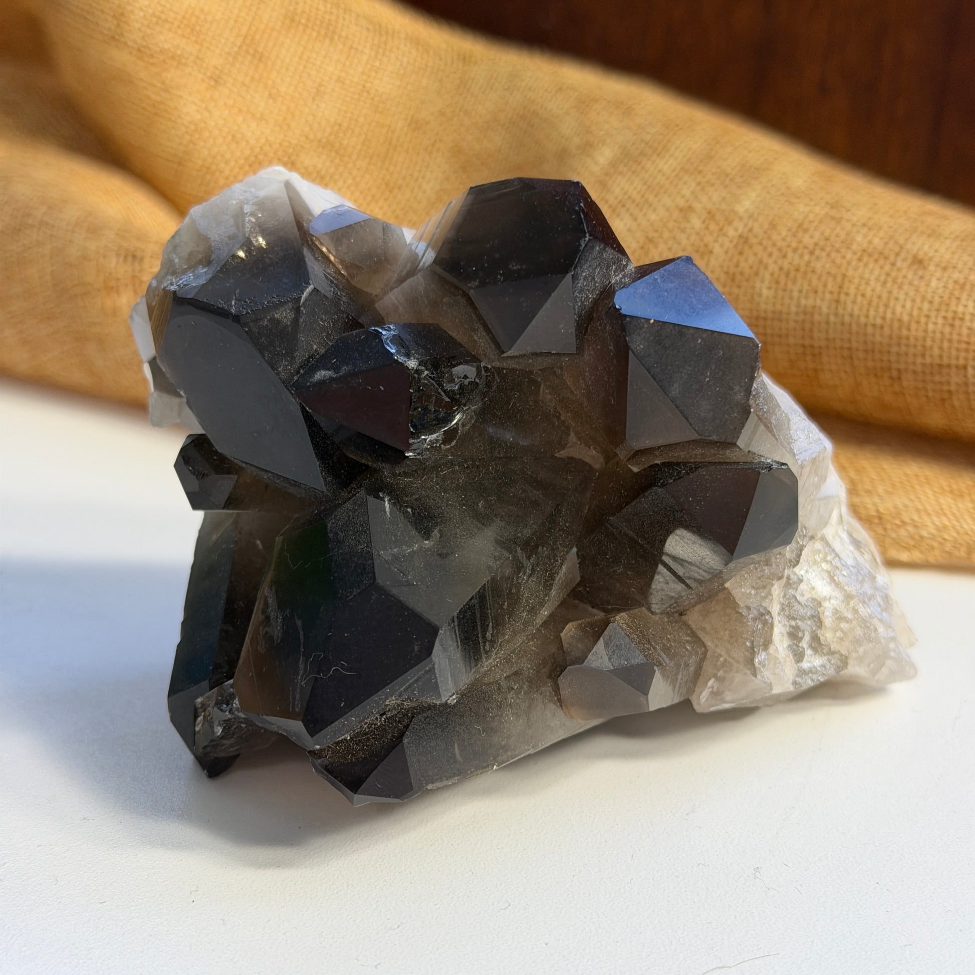 Smoky quartz cluster on a white surface with a beige fabric background