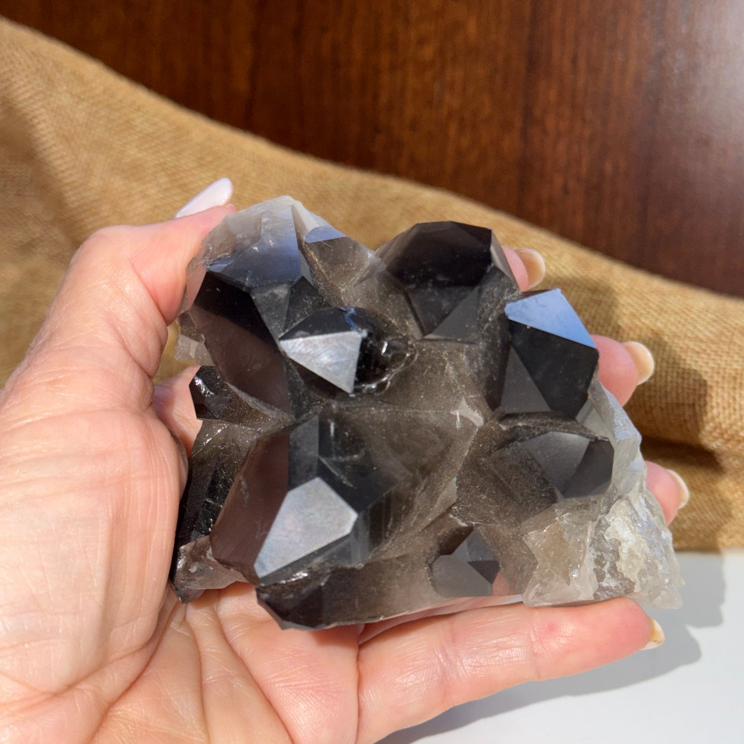 Hand holding a large crystal rock with a wooden surface in the background
