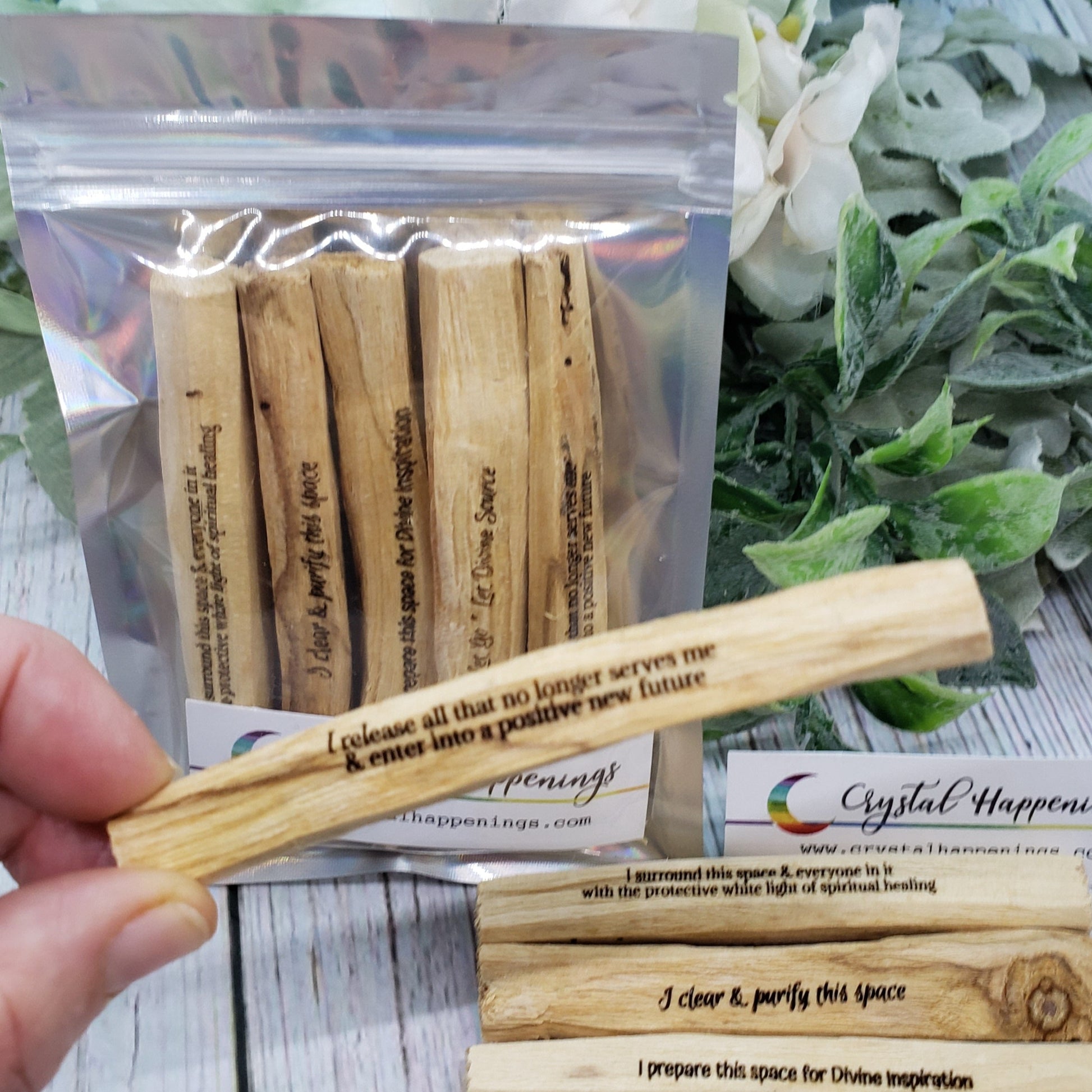 Female Hand Holding one Palo Mantra stick in front of packaged and loose Palo Mantra Gift Set
